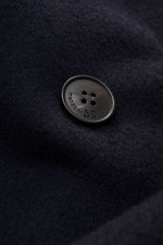 Nahaufnahme eines schwarzen Knopfs mit Prägung auf dunkelblauem Wollstoff, Detailansicht des Manzoni 24 Mäntel - U640.