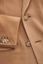 Nahaufnahme aus schräger Perspektive des Boglioli Cashmere Mantel camel, mit weichem Griff, Reverskragen, Kissing Buttons und Brusttasche.