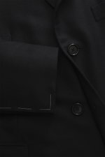 Nahaufnahme aus schräger Perspektive des schwarzen Cesare Attolini Cashmere Mantels mit weichem Griff, Slim Fit, Drei-Knopf-Leiste und fallendem Revers.