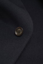 Close-up view of the Montecore Cashmere Coat navy showing a detailed shot of the pure cashmere fabric and a four-button style button with Montecore branding, highlighting its soft touch and fine texture. Luxurious through autumn and winter: MONTECORE pres