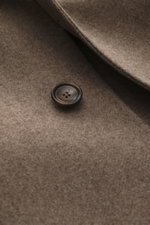 Nahaufnahme des graubraun melierten Tagliatore Mantels mit Fokus auf Knopf und Wollstoff, Detailaufnahme aus frontaler Perspektive.