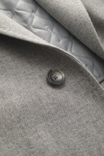 Tagliatore Mantel hellgrau meliert in Nahaufnahme von oben, reine Schurwolle, weicher Griff, Slim Fit, drei Knöpfe, fallendes Revers, halb gefüttert.