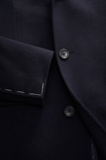 Close-up front view of the Tagliatore Cashmere Coat navy showing pure cashmere fabric, slim fit, tailored three-button style, notched lapel with logo pin, welted chest pocket, front flap pockets, unfinished sleeve cuffs with visible stitching, and smooth 