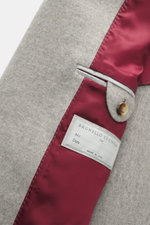 Close-up inside view of Brunello Cucinelli Cashmere Coat grey melange showing soft cashmere fabric, burgundy satin lining, label, and button detail.

Description: 
<p>Elegant understatement in luxurious material quality: The super soft cashmere coat from 