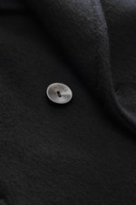 Close-up front view of the Agnona Cashmere Coat Black showing black pure cashmere fabric, wide lapel collar, and branded button.