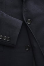 Nahaufnahme des Brioni Cashmere Mantel navy mit geradem Schnitt, Slim Fit, fallendem Revers, Drei-Knopf-Leiste, Brust- und Fronttaschen, gezeigt aus schräger Perspektive.