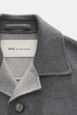 Close-up view of the Ami Paris Wool coat grey collar and button, showcasing its mix of virgin wool and cashmere, soft touch, regular fit, five-button placket, short notch lapel, slanted welt pockets, two inside pockets, and unconstructed design.