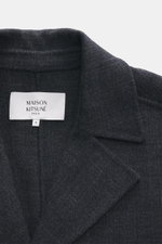 Close-up front view of Maison Kitsuné Coat dark grey melange showing notched collar and label, doubleface wool and microfiber, very soft touch, oversized fit, three-button placket, slanted welt pockets, back cape with ventilation slits, center back vent, 