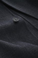 Close-up front perspective of Maison Kitsuné Coat dark grey melange showing black button with brand logo on soft doubleface wool and microfiber fabric, featuring very soft touch, oversized fit, three-button placket, notched collar, slanted welt pockets, b
