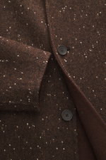 Close-up view of the Percival Coat 'Minnesota' brown/white melange fabric showing wool, microfiber, cotton mix with twill and slubs, featuring a five-button placket, turn-down collar, chest and side seam pockets with buttons, adjustable waist tabs, regula