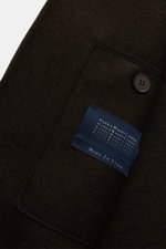 Close-up of the Harris Wharf London Wool coat dark brown showing the textured felted virgin wool fabric, a black button with red stitching, and the blue label, photographed from a top-down perspective.

<p>Timeless, pure, and well thought out: This unline