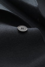 Close-up front view of Harris Wharf London Wollmantel navy showing a heavy felted pure new wool fabric and a large button with raw-edge finish.