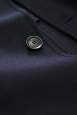 Close-up front detail of the Doppiaa Coat 'Aaladin' navy showing a black four-hole button on soft virgin wool blend fabric, photographed from above. Italian coolness to throw on: The 'Aaladin' coat by DOPPIAA made of wool blend can be perfectly combined w