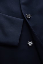 Close-up front view of the Lardini Wool Coat Navy showcasing light fabric of pure virgin wool, soft feel, regular fit, three-button placket, notch collar with flower pin, slanted welt pockets, center back vent, smooth lining fabric, and two inside pockets