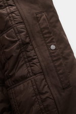 Nahaufnahme der Stone Island Jacke 'David-TC Ghost Piece' dunkelbraun, zeigt gestepptes Innenfutter und schräg überlappende Knopfleiste.