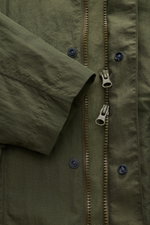 Close-up front view of the olive 04651/ A trip in a bag Mantel 'Travel Coat' oliv showing zipped two-way zipper, snap buttons, and sleeve cuff. Practical outdoor coat made of high-quality water-repellent, windproof microfiber with features: Regular Fit, w
