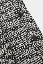 Nahaufnahme des 04651/ A trip in a bag Wende-Mantel 'Abstract' schwarz/offwhite mit abstraktem Muster, Fünf-Knopf-Leiste, Umlegekragen und schrägen Leistentaschen, fotografiert aus seitlicher Perspektive.