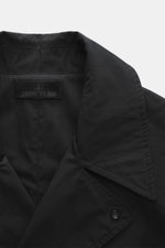 Close-up front view of the collar and label of the Stone Island Trenchcoat 'Ghost Piece' navy, made of pure cotton, Regular Fit, with smooth button placket, turn-down collar with tab, front pockets with flap and press studs, tonal compass badge on upper a