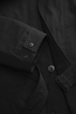 Close-up detail of Stone Island Trenchcoat 'Ghost Piece' navy, photographed from above, showing pure cotton fabric, regular fit, smooth button placket, turn-down collar with tab, front pockets with flap and press studs, tonal compass badge on upper arm, b