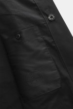 Close-up view of the Stone Island Trenchcoat 'Ghost Piece' navy showing smooth button placket and inside pocket with tonal compass badge, made of pure cotton, Regular Fit with turn-down collar with tab, front pockets with flap and press studs, buttoned sl