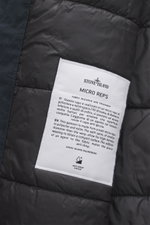 Close-up inside view of the Stone Island Short Coat 'Micro Reps' navy, showing quilted lining fabric, high-quality microfiber, smooth touch, warm Primaloft filling, and the label with fabric details.