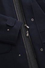 Nahaufnahme des Brunello Cucinelli Wollmantels navy in edler Doubleface-Verarbeitung, mit zwei-Wege-Reißverschluss, Kapuze und Knopfriegel am Ärmel.