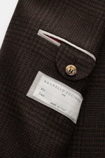 Close-up of the inside pocket of the Brunello Cucinelli Suit black/brown checked, showing fabric texture, button, and label. This suit by BRUNELLO CUCINELLI is what happens when Italian elegance meets luxurious handcraftsmanship. The unconstructed smart-c