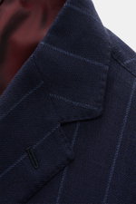 Close-up front angle of Stile Latino Anzug 'Vincenzo' navy gestreift jacket lapel showing fine chalk-stripes and textured fabric. Mix of cotton and wool, soft feel, slim fit. Tailored three-button style with notch lapel, classic breast pocket, piped hip p