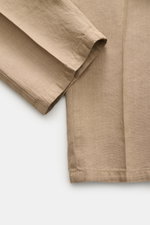 Nahaufnahme des Ärmels und Teils der Vorderseite des Santaniello Anzug taupe aus reinem Leinen, vintage Optik, weicher Griff, Slim Fit, unstrukturierter Zwei-Knopf-Sakko mit fallendem Revers, aufgenommen aus schräger Draufsicht.