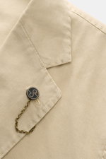 Close-up, top-down view of the Santaniello Anzug sand, showing the fine cotton twill fabric, soft texture, tailored two-button lapel, with a decorative chain and button detail. Lässige Eleganz mit Stil: Dieser Anzug von SANTANIELLO überzeugt mit feinstem 