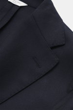 Close-up angled view of the Boglioli Suit 'K. Jacket' navy lapel, showcasing fine tonal herringbone pure virgin wool fabric.