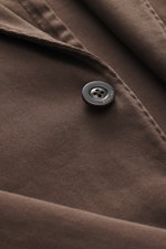 Nahaufnahme des graubraunen Boglioli Anzugs 'K. Jacket' aus elastischer Baumwolle mit Knopf und feinem Twill, seitlich fotografiert.