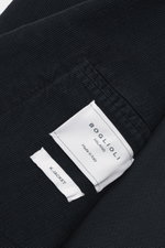 Nahaufnahme des navyfarbenen Boglioli Cordanzugs 'K. Jacket' mit feinem Cordstoff, Etiketten und weichem Griff, fotografiert aus schräger Perspektive.