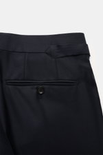 Close-up rear view of the Tom Ford Anzug 'Shelton' navy trousers showing pure wool fabric, side adjuster, buttoned welt pocket, and fine weave texture.