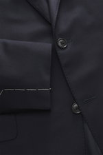 Close-up front view of Belvest Suit navy jacket showing pure super 150's wool fabric with soft feel, slim fit, tailored two-button style, notched lapel with pin, classic breast pocket, hip pockets with flap, unfinished sleeve cuffs, and smooth lining fabr