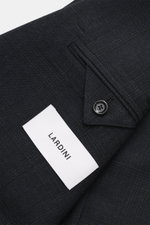 Close-up angled view of Lardini Suit dark navy melange cuff with button, subtle check pattern, and white brand label, made of pure new wool.