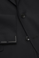 Close-up front view of the Tagliatore Suit 'Vesuvio' black jacket showing soft Super 120's virgin wool fabric, two-button style, notched lapel with pin, and classic breast pocket with precise tailoring.