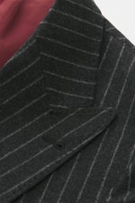 Brunello Cucinelli Anzug dunkelgrau/hellgrau gestreift, Detailaufnahme des Unconstructed-Sakkos mit Spitzrevers und rotem Innenfutter, textile Struktur sichtbar.