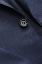 Close-up front view of the Brioni Suit 'Brunico' navy melange showing the smooth textured pure wool fabric, tailored two-button jacket with notched lapel and black button, highlighting the slim fit and high-quality silk-wool blend for elegant occasions.