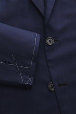 Close-up front view of Brioni Suit 'Brunico' navy showing tailored two-button jacket with notched lapel, soft wool-silk blend fabric, and unfinished sleeve cuffs with white basting stitches.