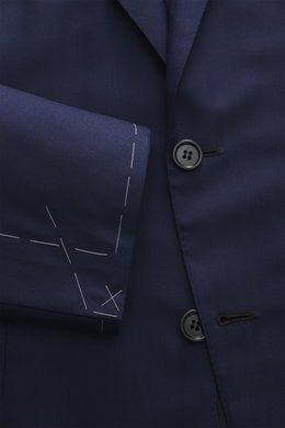 Close-up front view of Brioni Suit 'Brunico' navy showing tailored two-button jacket with notched lapel, soft wool-silk blend fabric, and unfinished sleeve cuffs with white basting stitches.