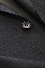 Close-up, top-down view of the Zegna Anzug 'Milano Trofeo' schwarz fabric, showcasing the slim fit suit's pure wool texture, soft feel, and button detail. The blazer features a tailored two-button style with a notch lapel, chest pocket, flap hip pockets, 