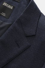 Close-up angled view of Zegna Suit 'Trofeo' navy melange jacket showing subtle check pattern, notched lapel, and ZEGNA label inside. The classic 'Trofeo' by ZEGNA impresses with its versatility and exclusive wool quality, making the suit a safe choice for