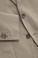 Nahaufnahme des Santaniello Anzug taupe aus Baumwoll-Twill, Fokus auf tailliertes Sakko mit Kissing Buttons, fotografiert von oben.