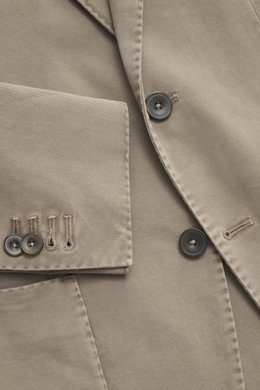 Nahaufnahme des Santaniello Anzug taupe aus Baumwoll-Twill, Fokus auf tailliertes Sakko mit Kissing Buttons, fotografiert von oben.