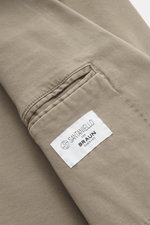 Nahaufnahme des Santaniello Anzugs taupe aus Baumwoll-Twill, Fokus auf leicht elastische, weiche Stoffstruktur und Taschendetail mit Markenlabel.