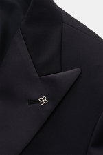 Tagliatore Tuxedo 'Napoli' dark navy close-up of pointed lapel with satin facing and signature pin, photographed from above front left. Italian eveningwear to meet the dress code: Draw attention to yourself in style with the elegant tuxedo 'Napoli' in pur