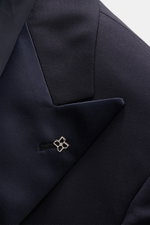 Close-up front angle of Tagliatore Tuxedo navy lapel showing satin-faced pointed lapel, signature pin, and smooth pure Super 110'S virgin wool fabric.

<p>Italian evening wear for elegant occasions: Draw attention to yourself in style with this classy tux
