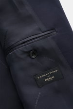 Close-up inside view of the Tagliatore Tuxedo navy showing the smooth satin lining, breast pocket, and branded label, photographed from above.