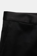 Black satin waistband detail of Tagliatore Tuxedo black trousers, photographed close-up from a side perspective.